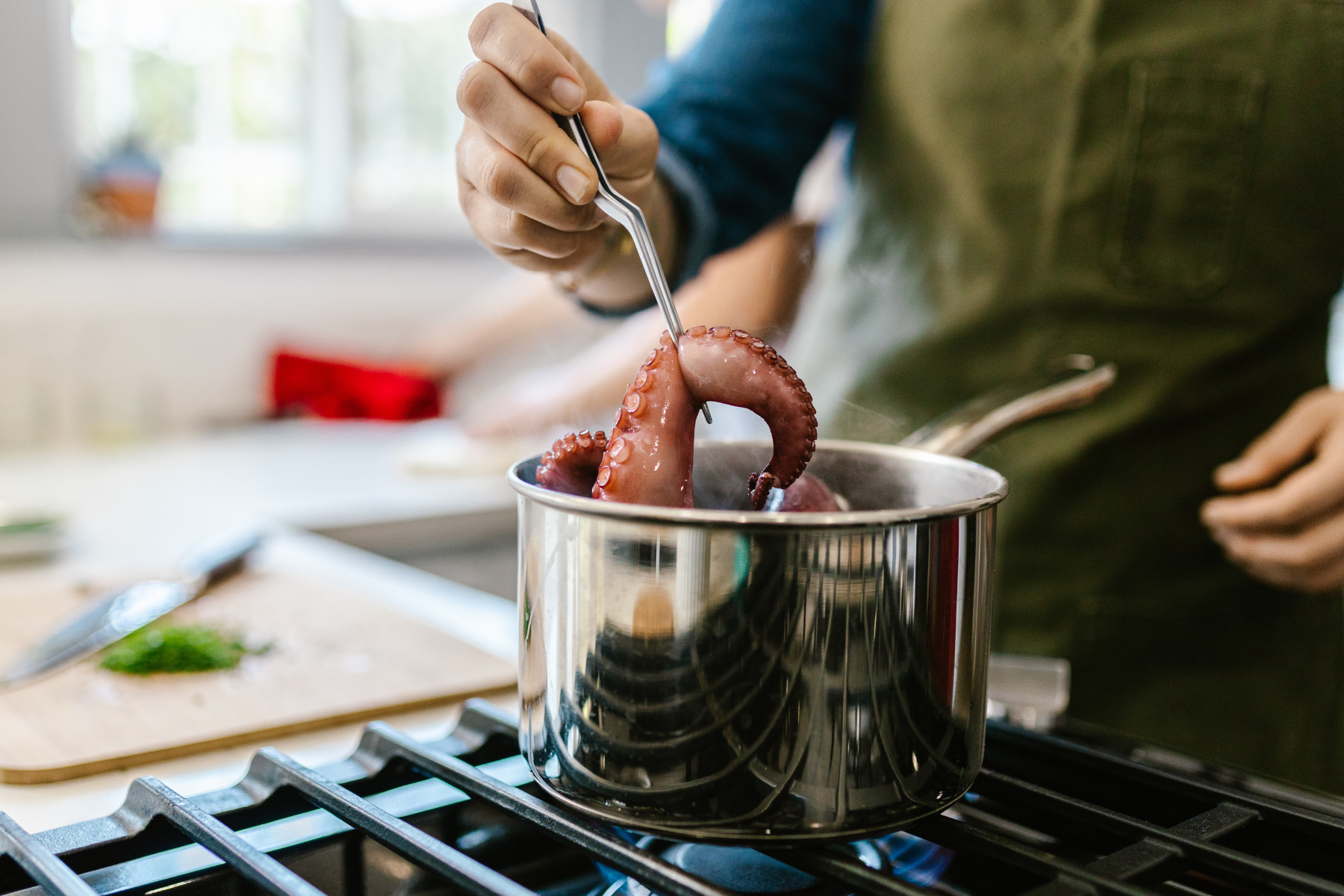 鍋から茹でたタコを取り出す男性